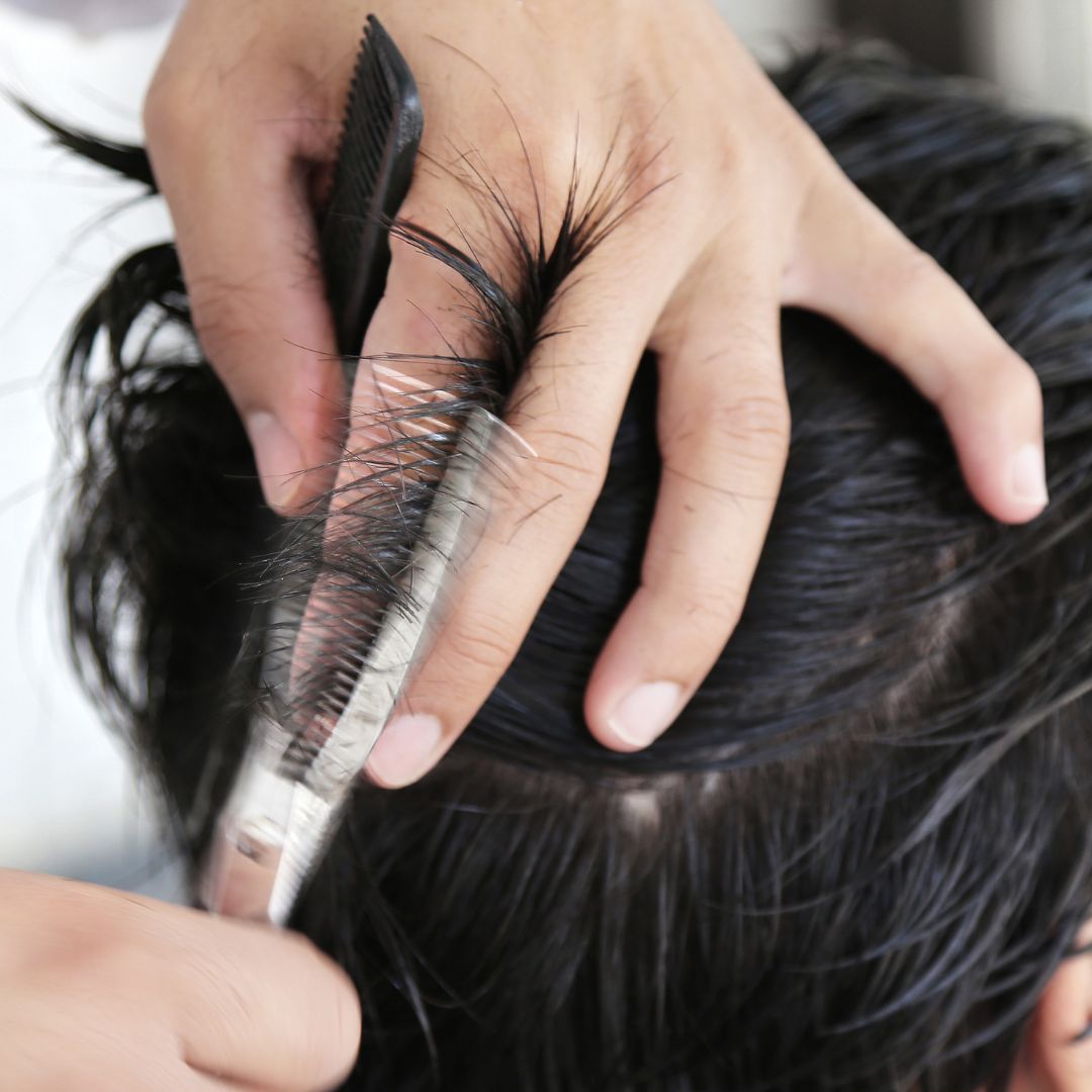 a man with longer hair getting their hair cut